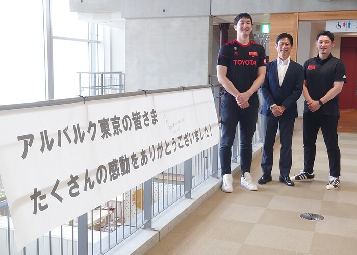 アルバルク東京の皆様にサインをいただいた横断幕の横に並んで記念撮影
