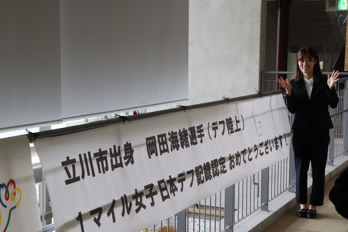 サインを書いた横断幕の横に立つ岡田選手