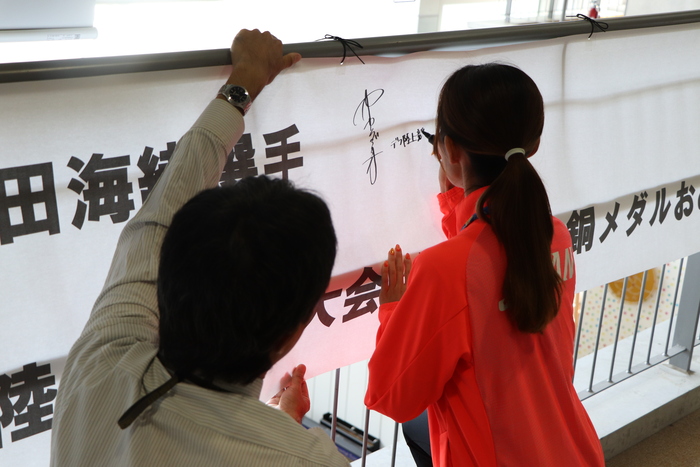 横断幕にサインをする岡田選手