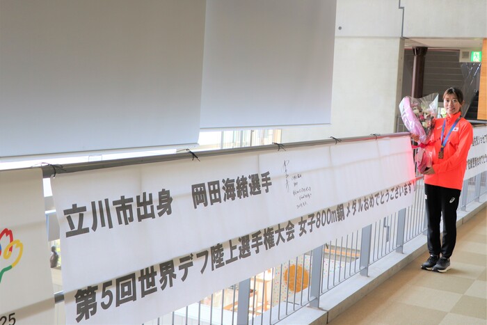 サインをしていただいた横断幕の横に立ち、笑顔の岡田選手