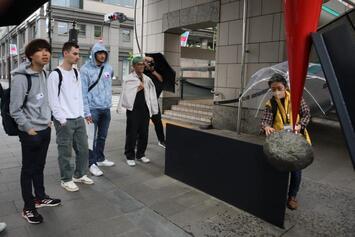 写真:ファーレ倶楽部のガイドの話を熱心に訊く留学生たち