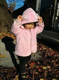 写真：落ち葉で遊ぶ元気な女の子