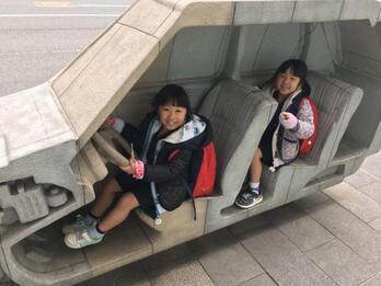 写真：自動車の形をしたアートに座る女の子