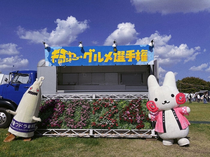 イベント看板の前でウドラと記念撮影をするくるりん