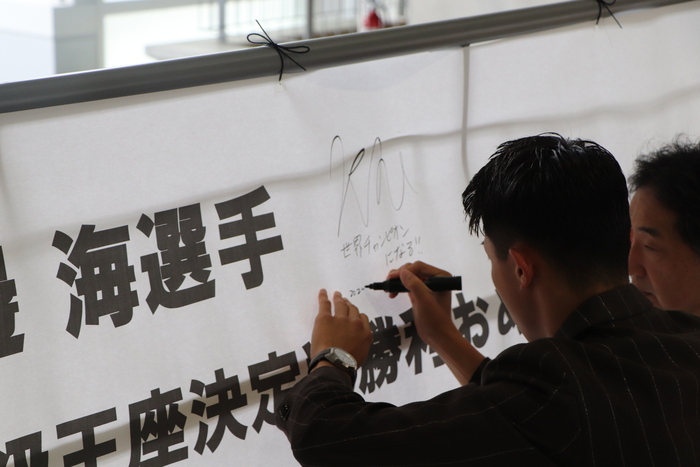 渡邊海選手が横断幕にサインをしている様子