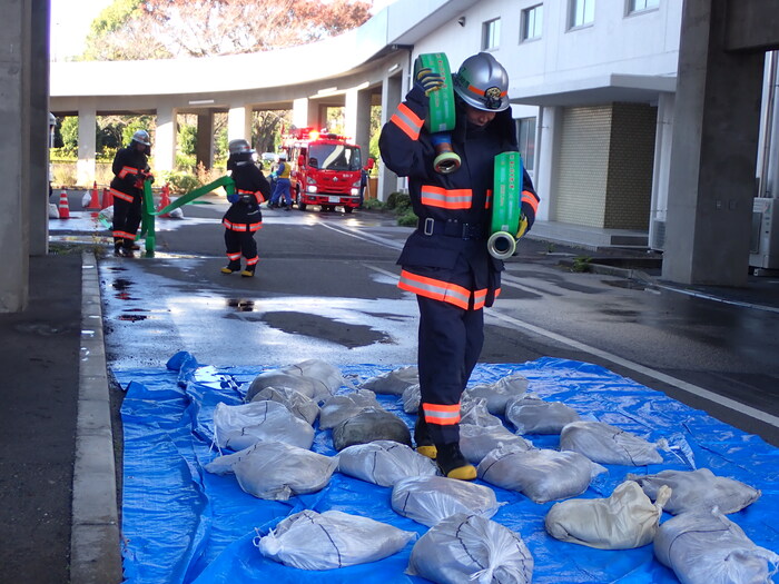 震災時の消火活動を想定、ホースを担いで瓦礫等の中を進む訓練の様子です