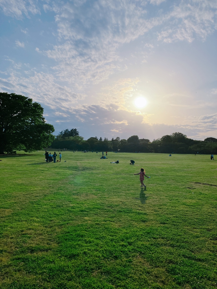 写真：夕焼け空の下で原っぱを走る少女
