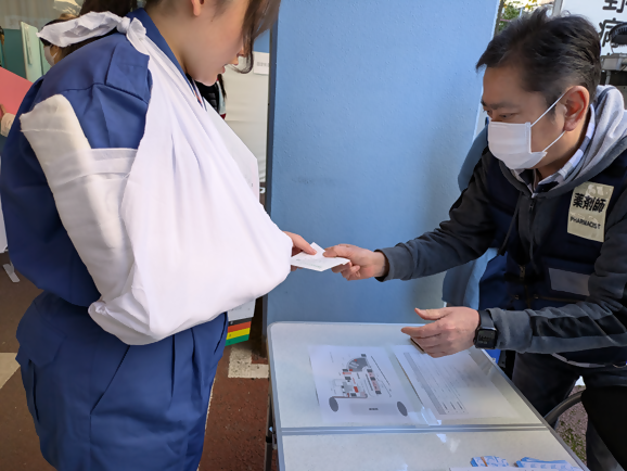 　傷病者が薬剤師より薬を受け取る様子
